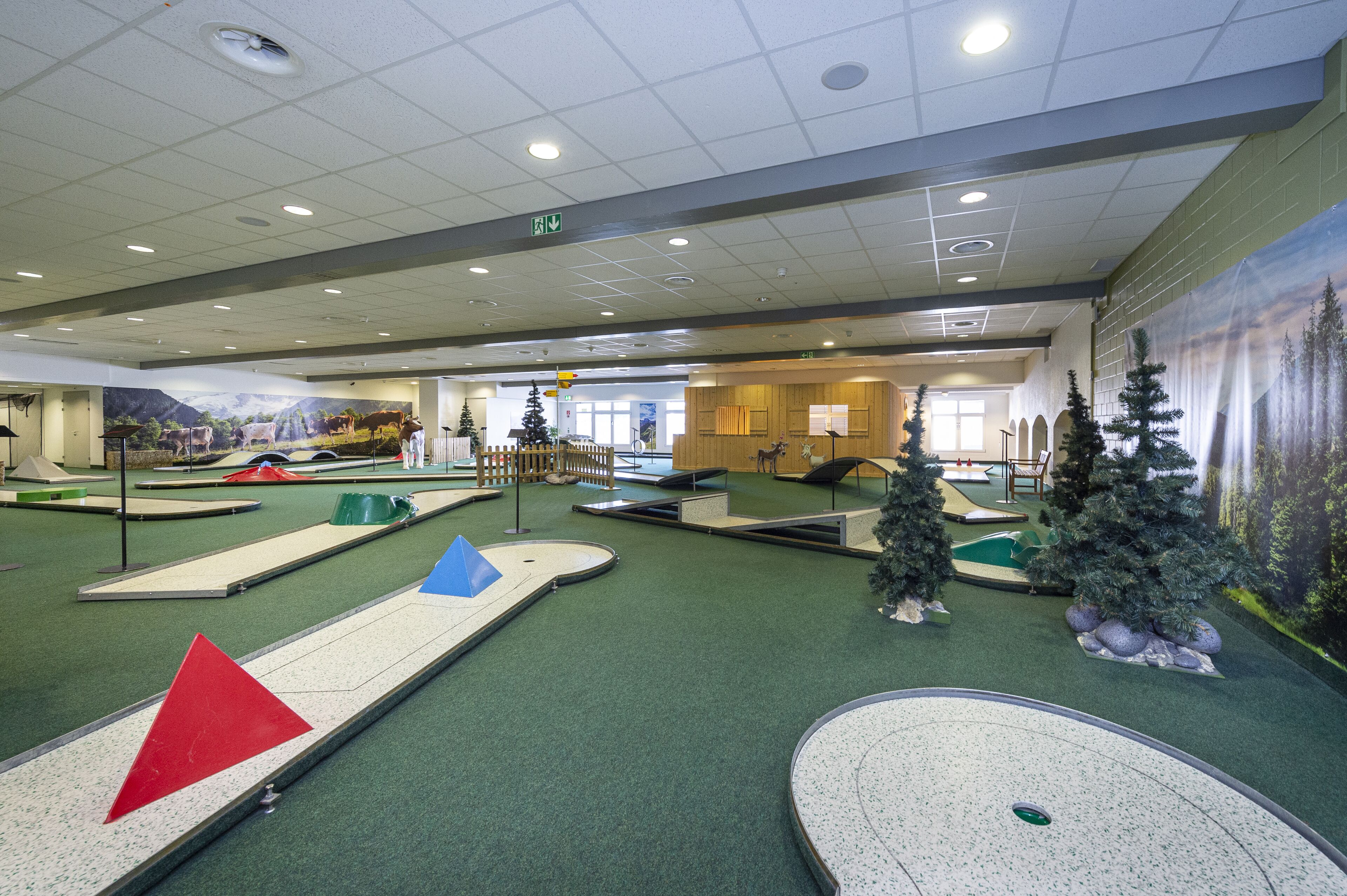 An indoor miniature golf course with various obstacles and a Christmas tree.