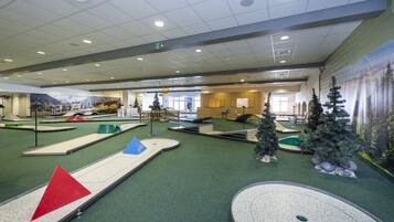 An indoor miniature golf course with various obstacles and a Christmas tree.