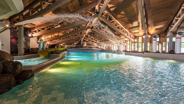 Una piscina interior con techo de madera y agua cristalina.
