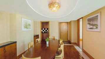 A conference room with a wooden table, chairs, a potted plant, and framed artwork on the walls.