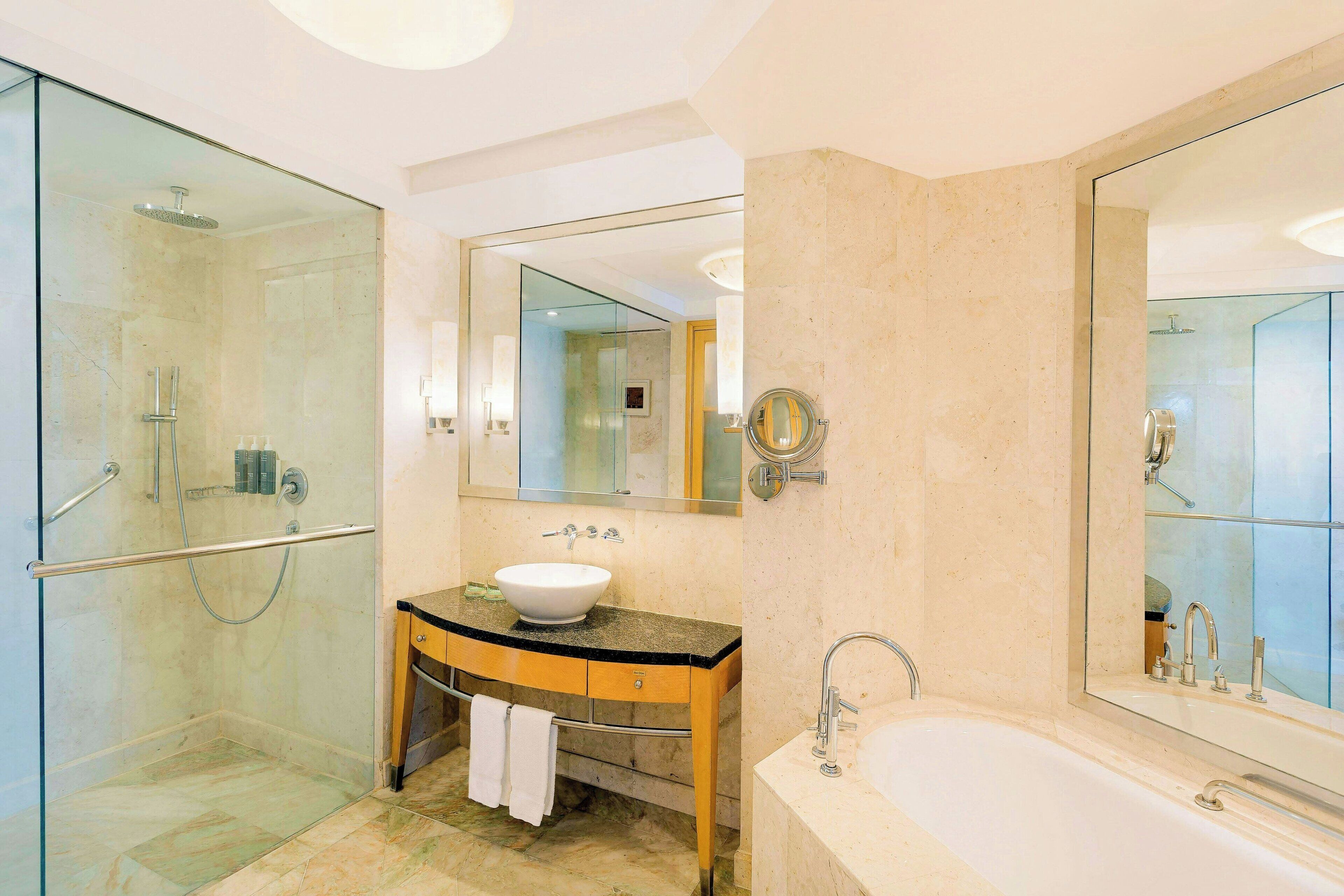 A modern bathroom with a glass-enclosed shower, a vanity with a sink, and a large mirror.