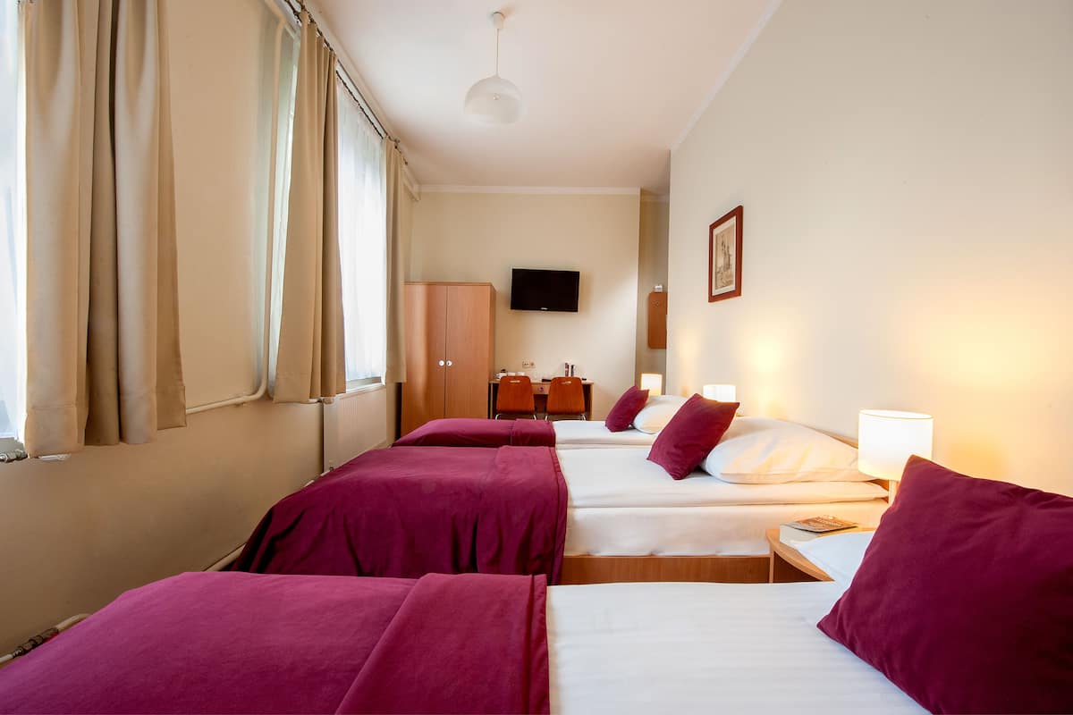 A hotel room with two beds, a desk, a chair, a TV, and a wardrobe.