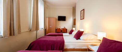 A hotel room with two beds, a desk, a chair, a television, and a window with curtains.