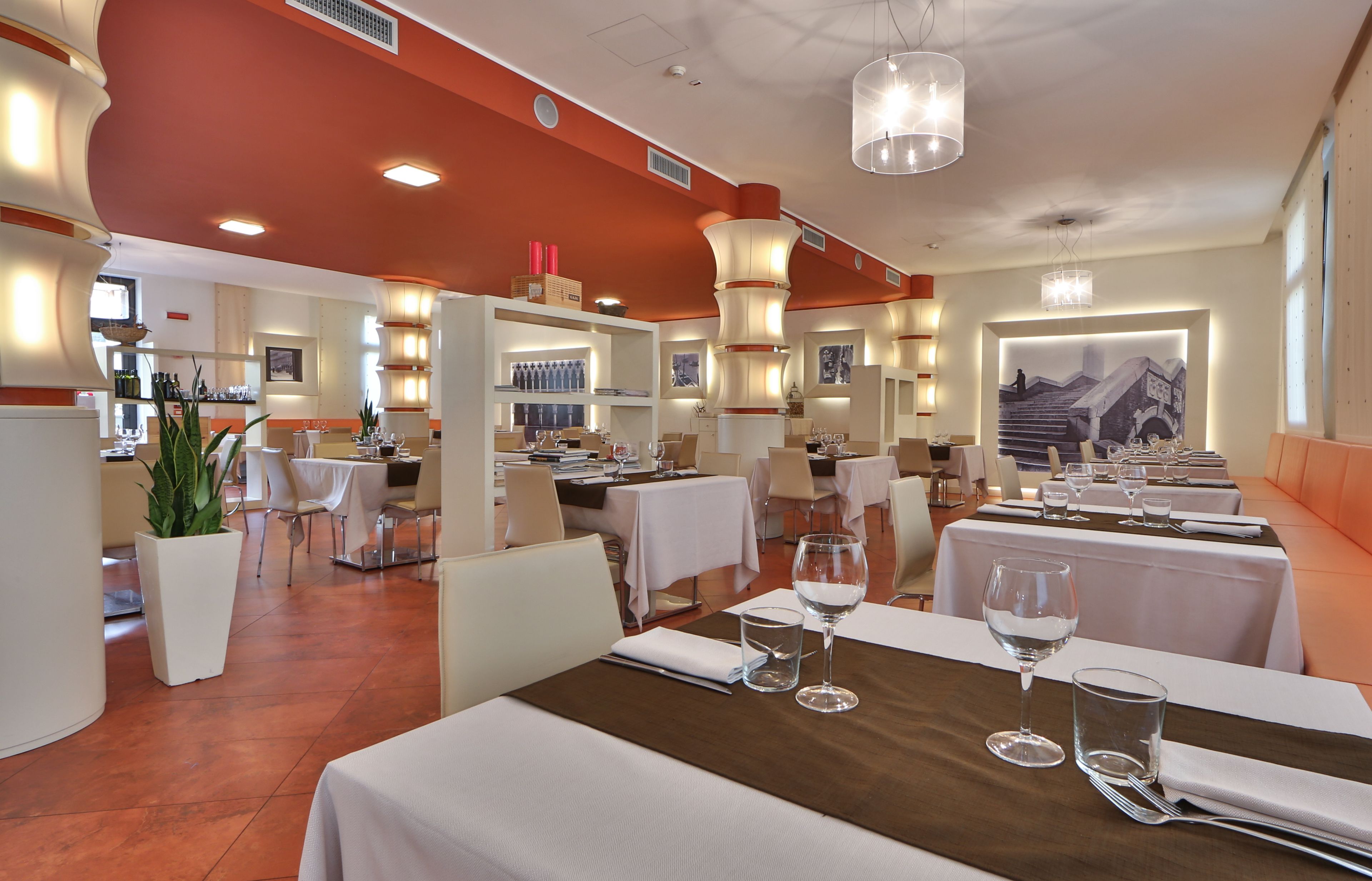 A restaurant with tables set for dining, featuring a modern interior with white and orange decor.