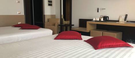 Habitación de hotel con dos camas, un escritorio, una silla, un televisor y un espejo.