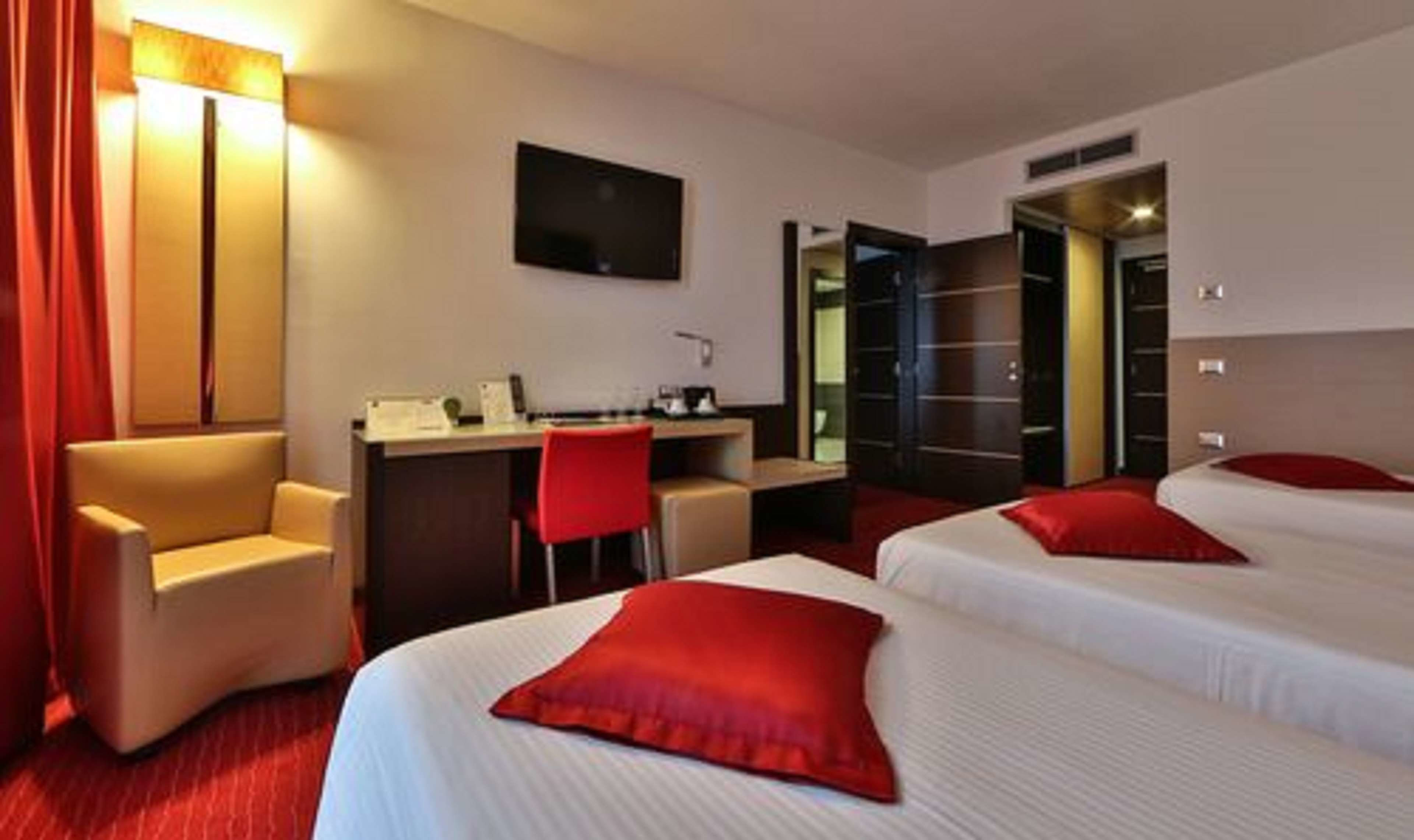 Una habitación de hotel con dos camas, un escritorio, una silla y un televisor.