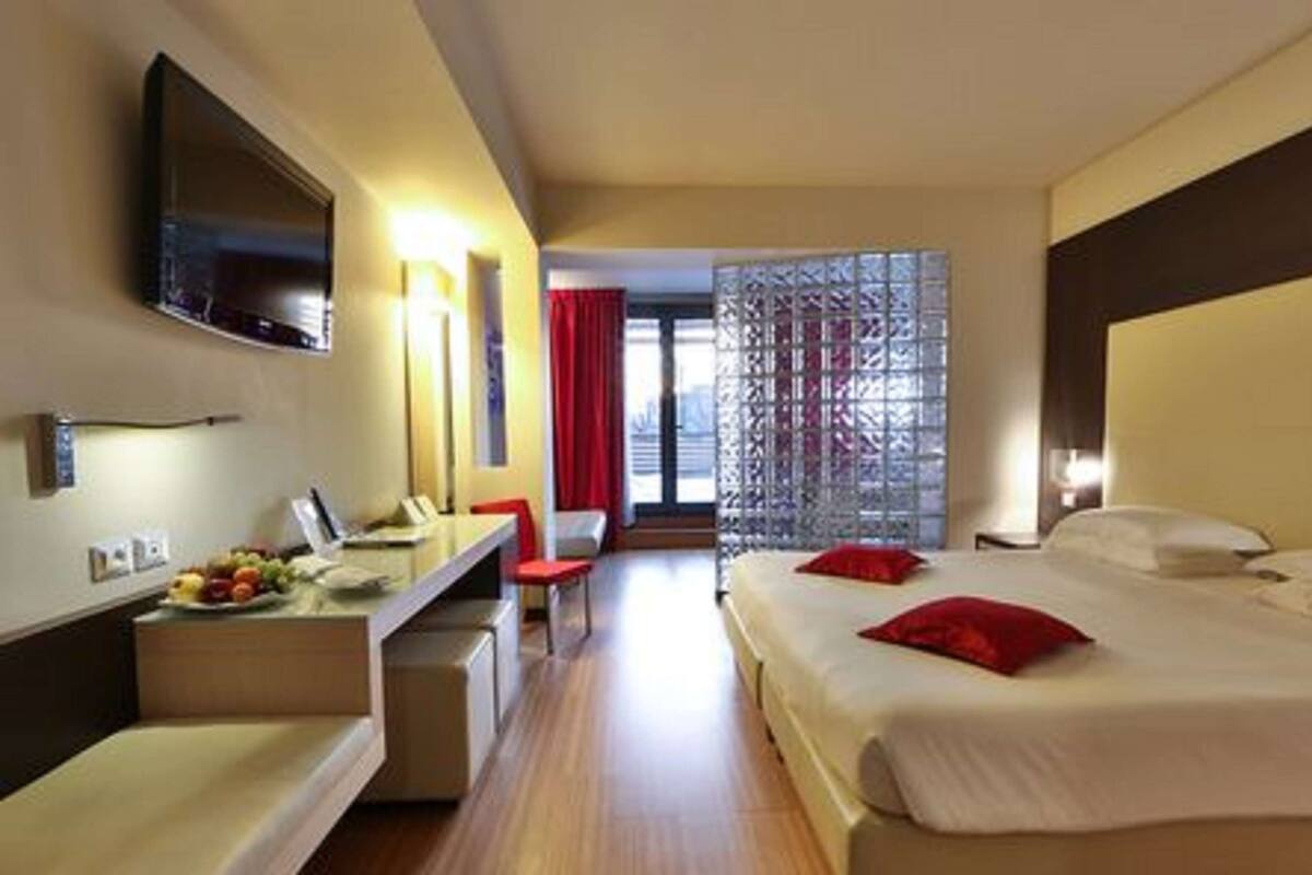 Une chambre d’hôtel comprenant un lit, un bureau avec un ordinateur, une chaise et un téléviseur.