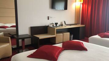 Habitación de hotel con dos camas, un escritorio, un televisor y una cortina roja.