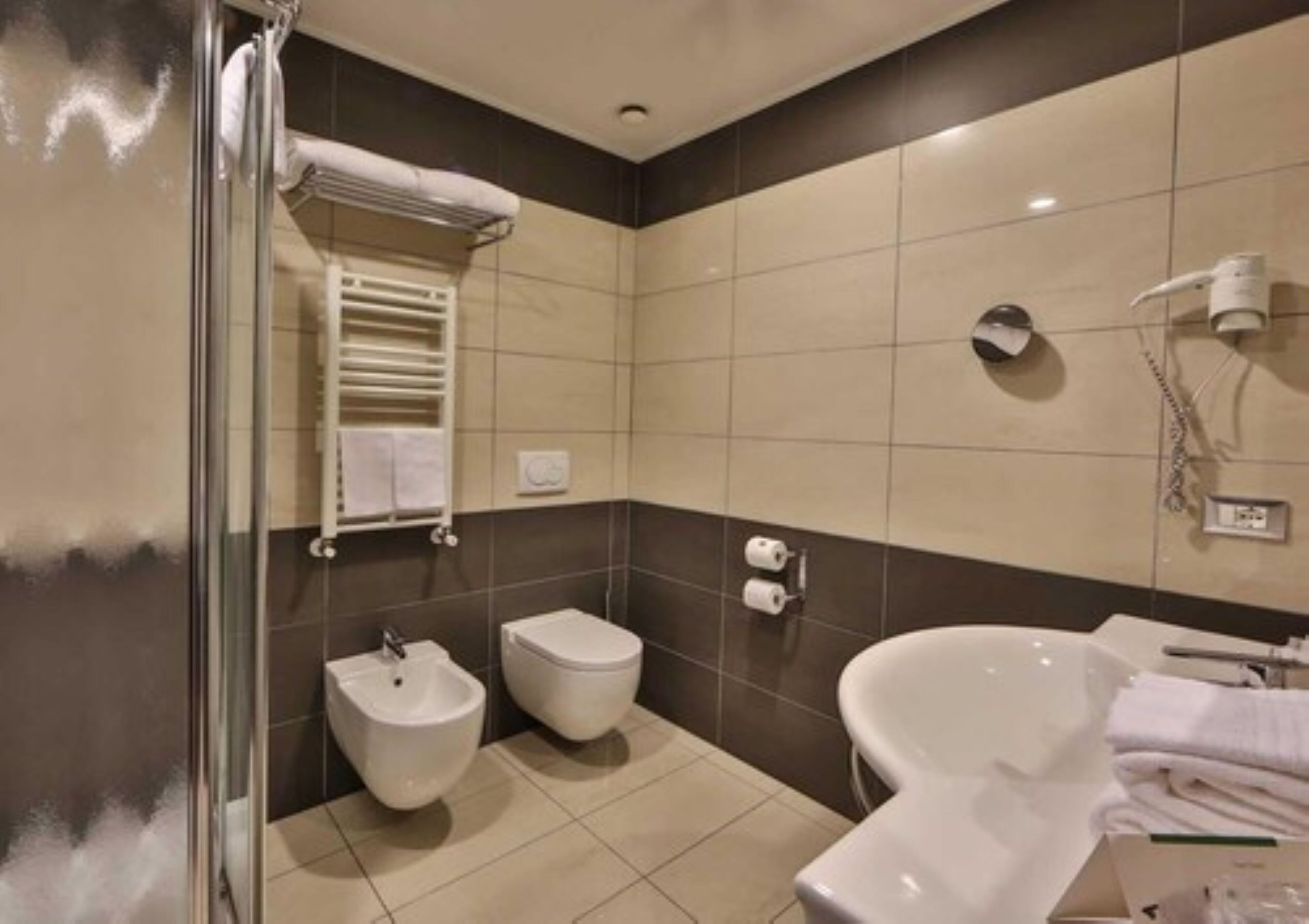 A modern bathroom with a bidet, toilet, and a large bathtub.