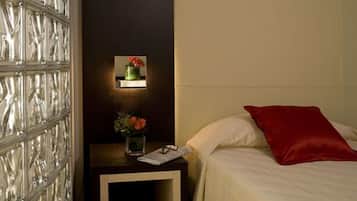 Una habitación de hotel con una cama, una mesita de noche y una lámpara fijada a la pared.