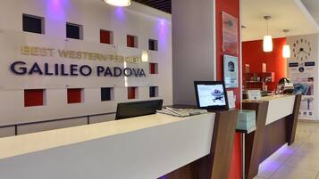 A hotel reception desk with a sign reading "BEST WESTERN PREMIER GALILEO PADOVA".