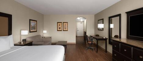 Een hotelkamer met een groot bed, een bureau, een stoel, een dressoir en een televisietoestel.