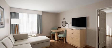 Una habitación de hotel moderna con sofá, escritorio, televisor y mesa de comedor.