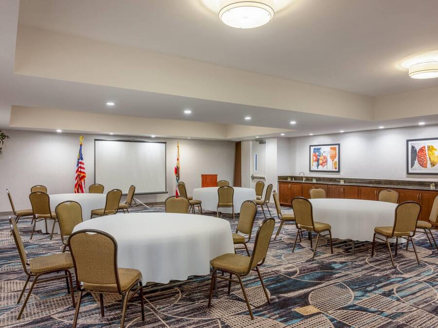 A conference room with round tables and chairs, flags, and framed artwork on the walls.
