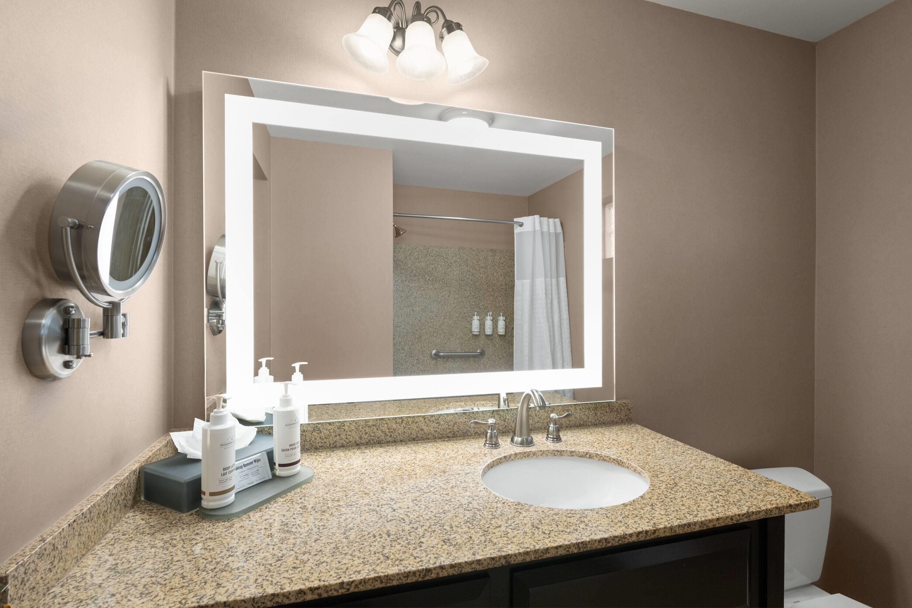 A bathroom with a large mirror, a sink, and a toilet.