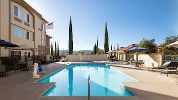 Een buitenzwembad, ligstoelen bij het zwembad