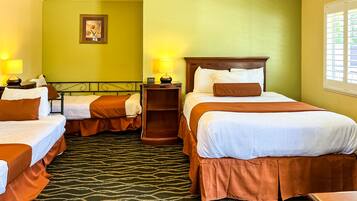 A hotel room with two single beds, a nightstand with a lamp, a wooden headboard, and a framed picture on the wall.
