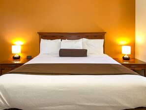 Une chambre d’hôtel avec un grand lit, deux lampes de chevet et une tête de lit en bois.
