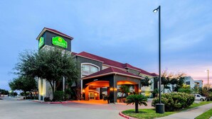 Un hotel con un letrero llamativo, un acceso cubierto y un área de estacionamiento.