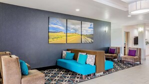Un vestíbulo con un sofá azul, sillones color beige y una alfombra estampada.