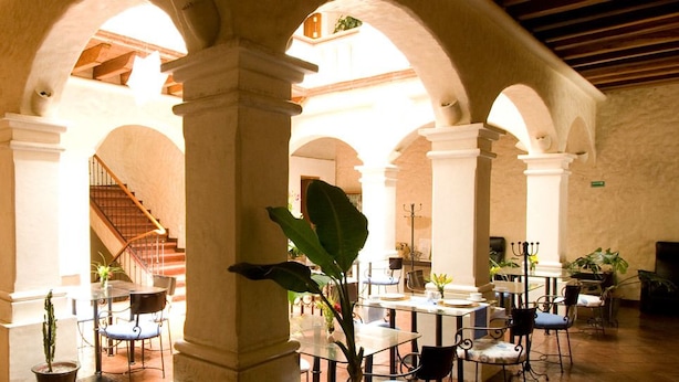 A spacious indoor courtyard with arches, potted plants, and a staircase.
