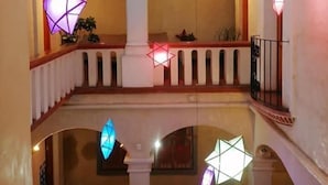 A multi-level interior with arched balconies and hanging geometric light fixtures.
