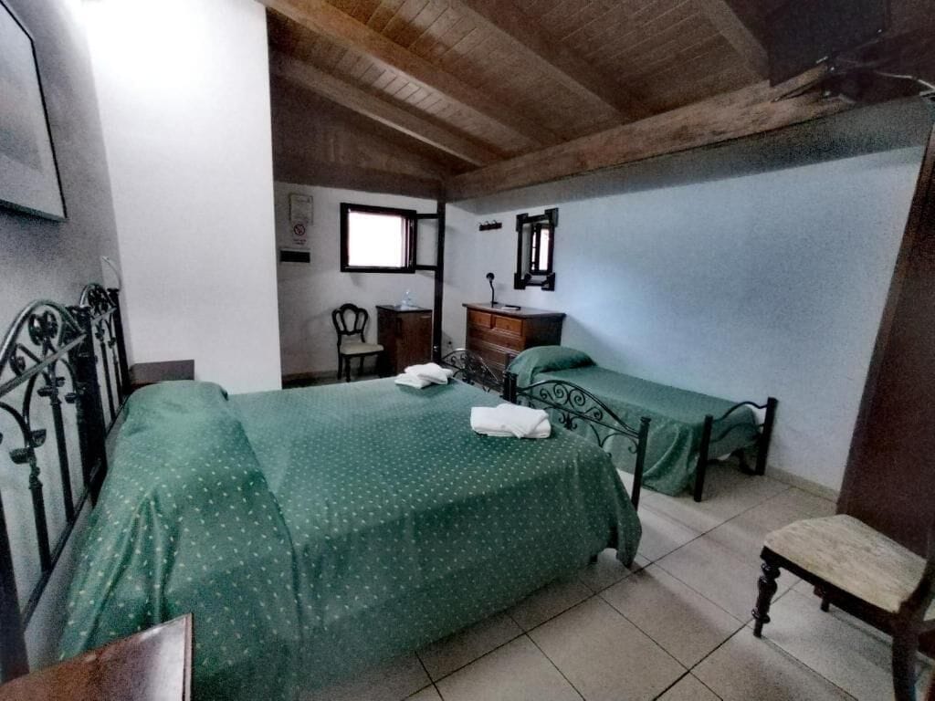 Une chambre avec deux lits, une chaise en bois, un bureau et une fenêtre.