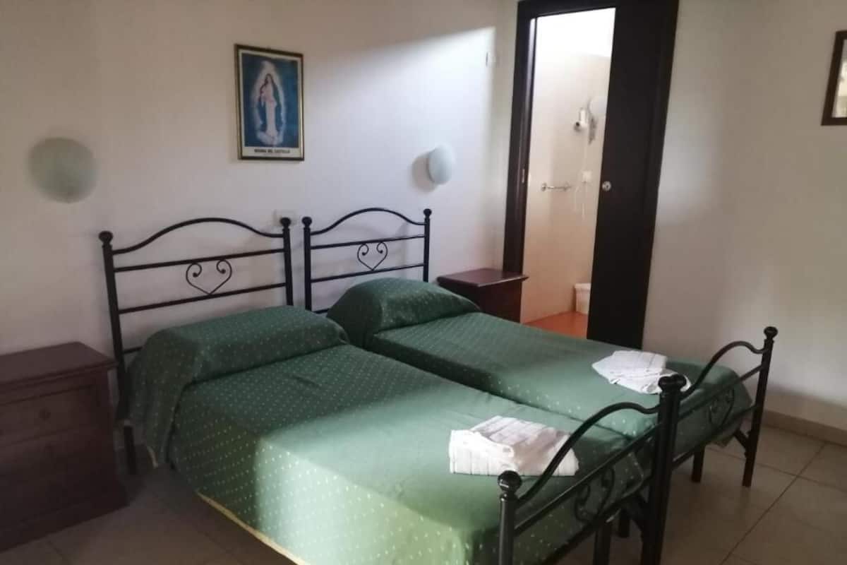 A bedroom with a bed, a nightstand, a dresser, and a door leading to a bathroom.