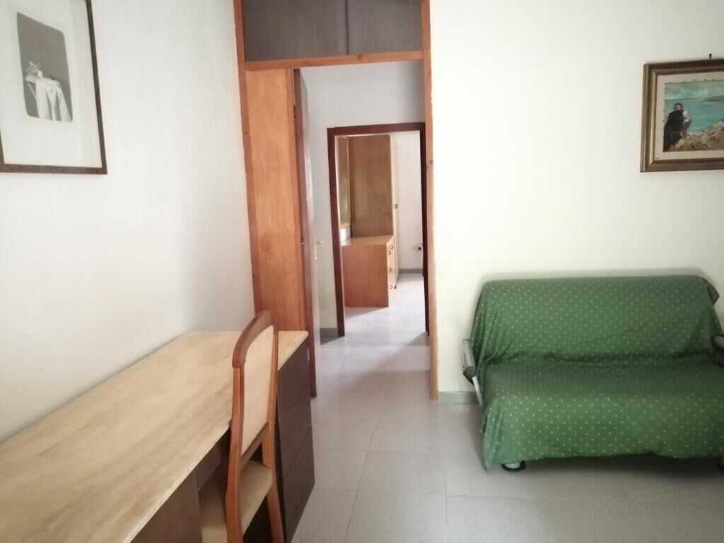 Una habitación con un escritorio de madera, un sofá verde y un cuadro en la pared.