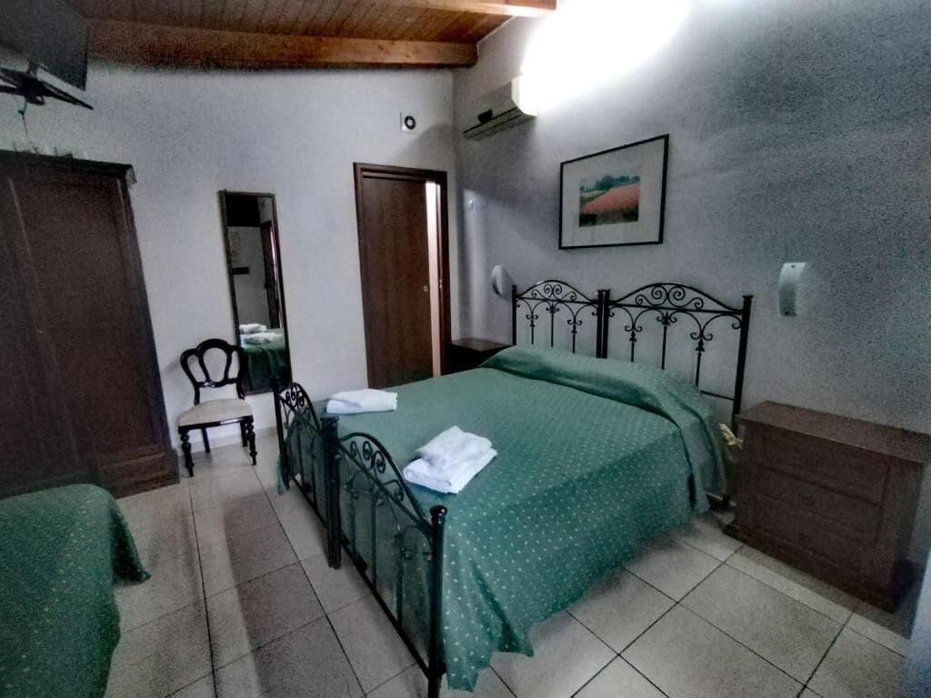 A bedroom with a bed, a chair, a dresser, a mirror, and a picture on the wall.
