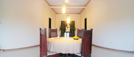 A dining area with a round table, chairs, and pendant lighting.