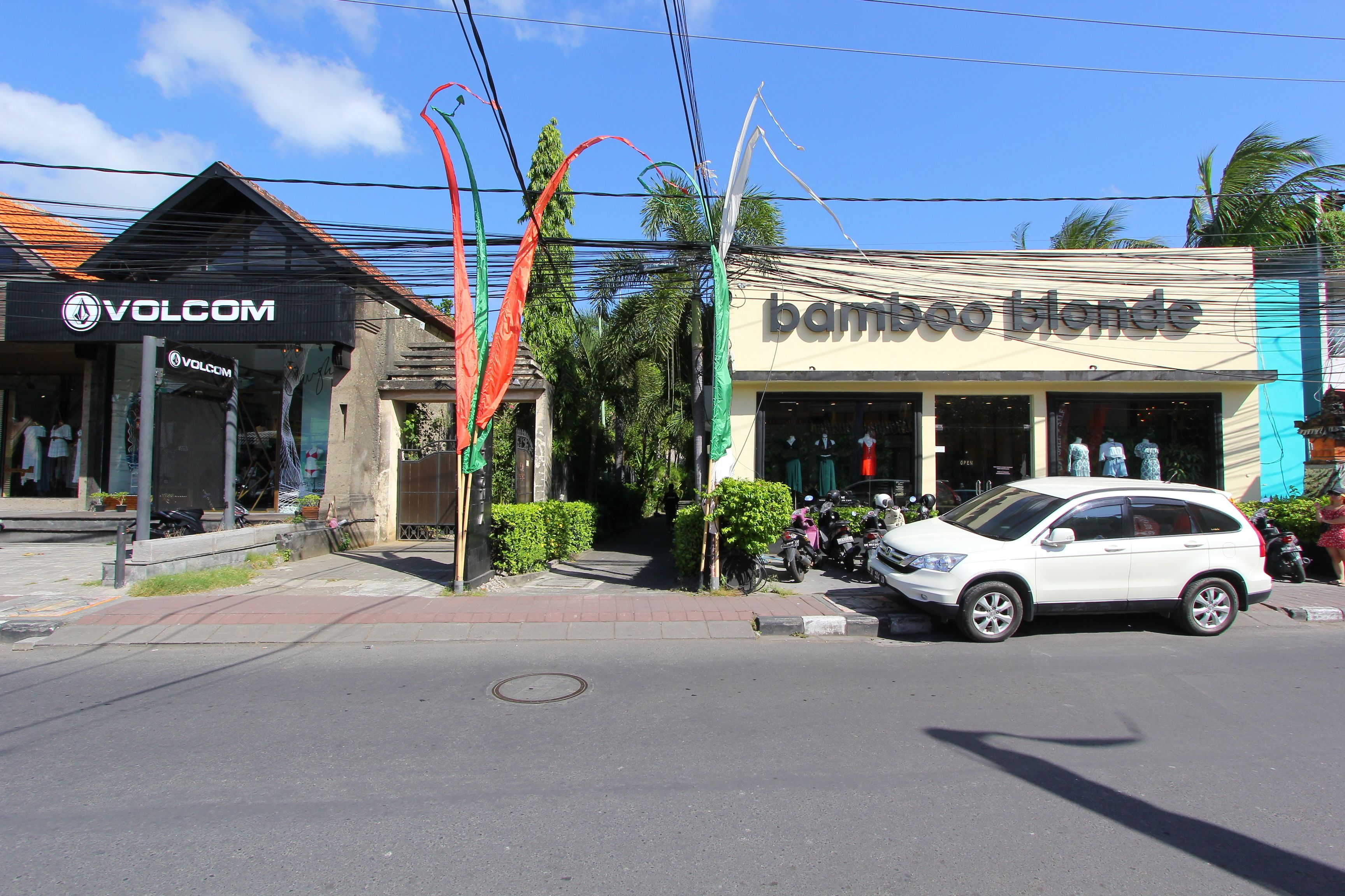 A street view with a white car parked in front of a store named 'bamboo blonde'.