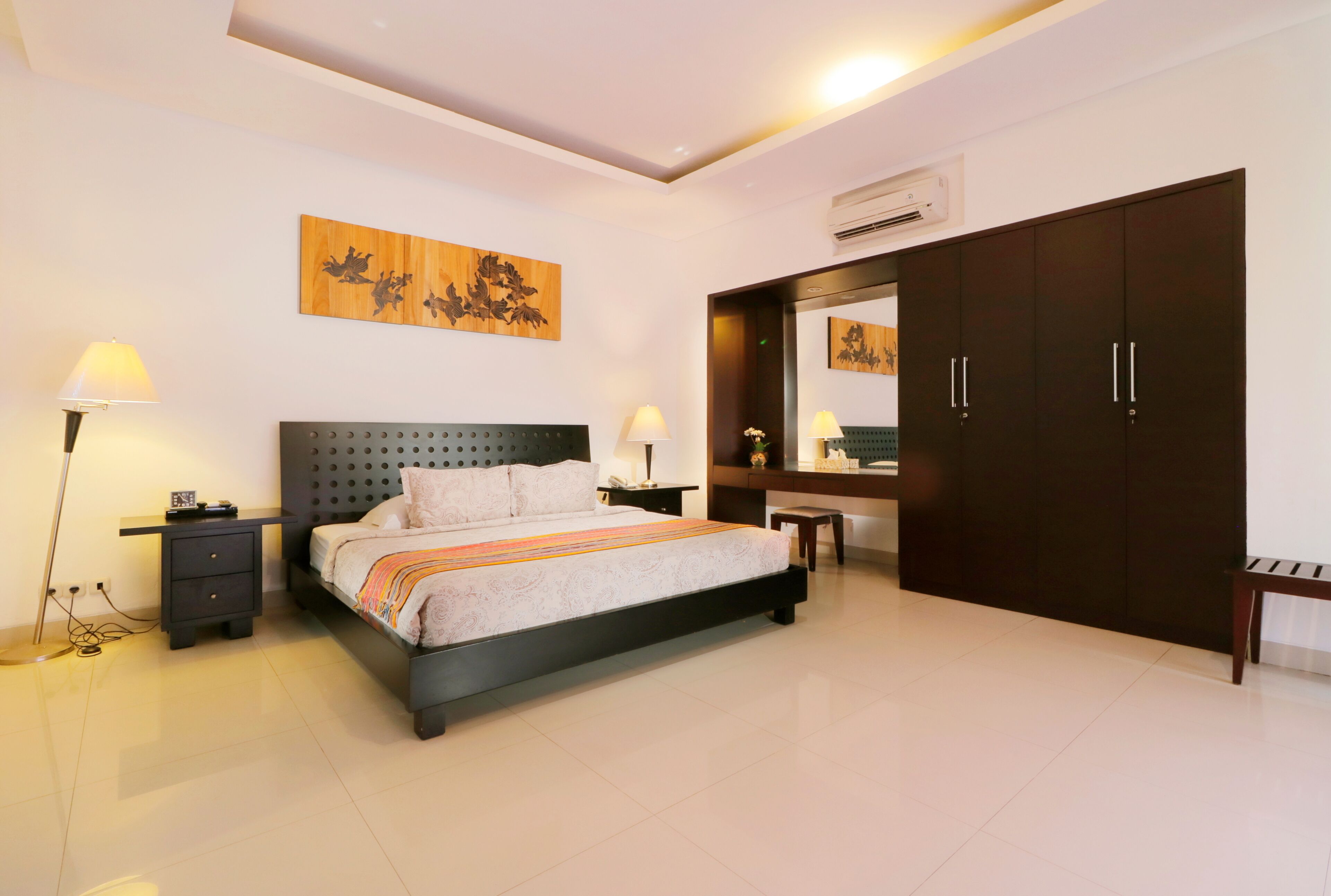 A modern bedroom with a large bed, bedside tables, a wardrobe, and artwork on the walls.