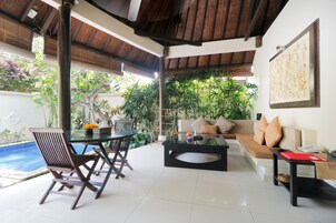 Un espacio moderno con piscina, un sofá y una mesa de comedor.