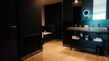 Un baño moderno con paredes oscuras, un espejo grande y dos lavamanos.