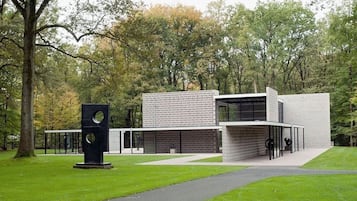 A modern building with a unique geometric design, surrounded by a lush green park.