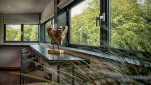 Un interior moderno con ventanas amplias, una escultura de madera y sillas a rayas.