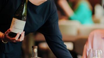Una persona sosteniendo una botella de vino y sirviéndolo en una copa.