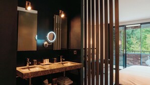 Un baño moderno con dos lavamanos, un espejo grande y vistas a un balcón con vegetación.