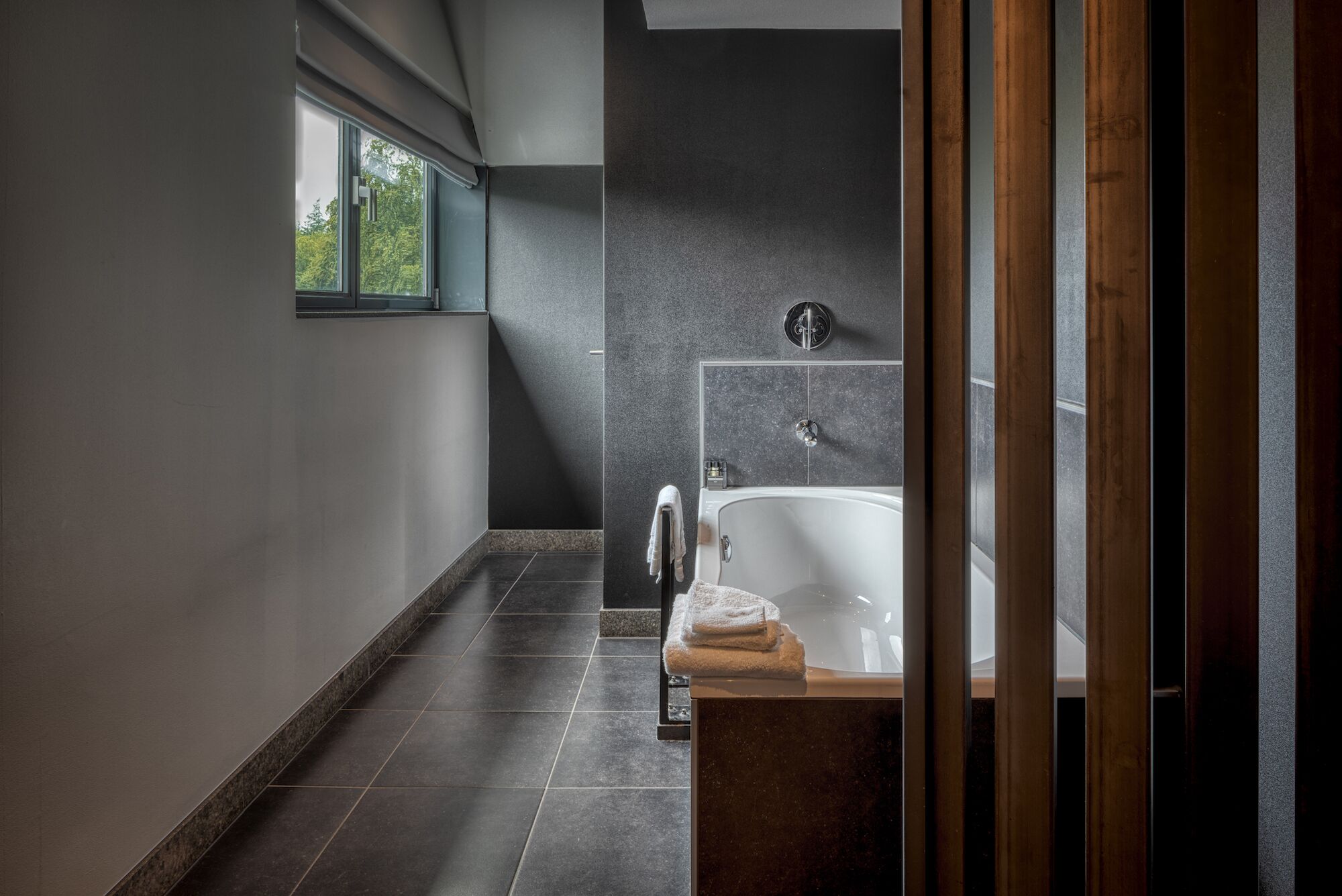 Ein modernes Badezimmer mit Badewanne, Handtuchhalter und einem Fenster, das für natürliches Licht sorgt.