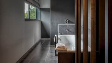 Ein modernes Badezimmer mit Badewanne, Handtuchhalter und einem Fenster, das für natürliches Licht sorgt.