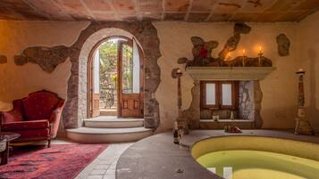 Una habitación con chimenea de piedra, un sillón rojo, una piscina y una vista a través de una puerta.