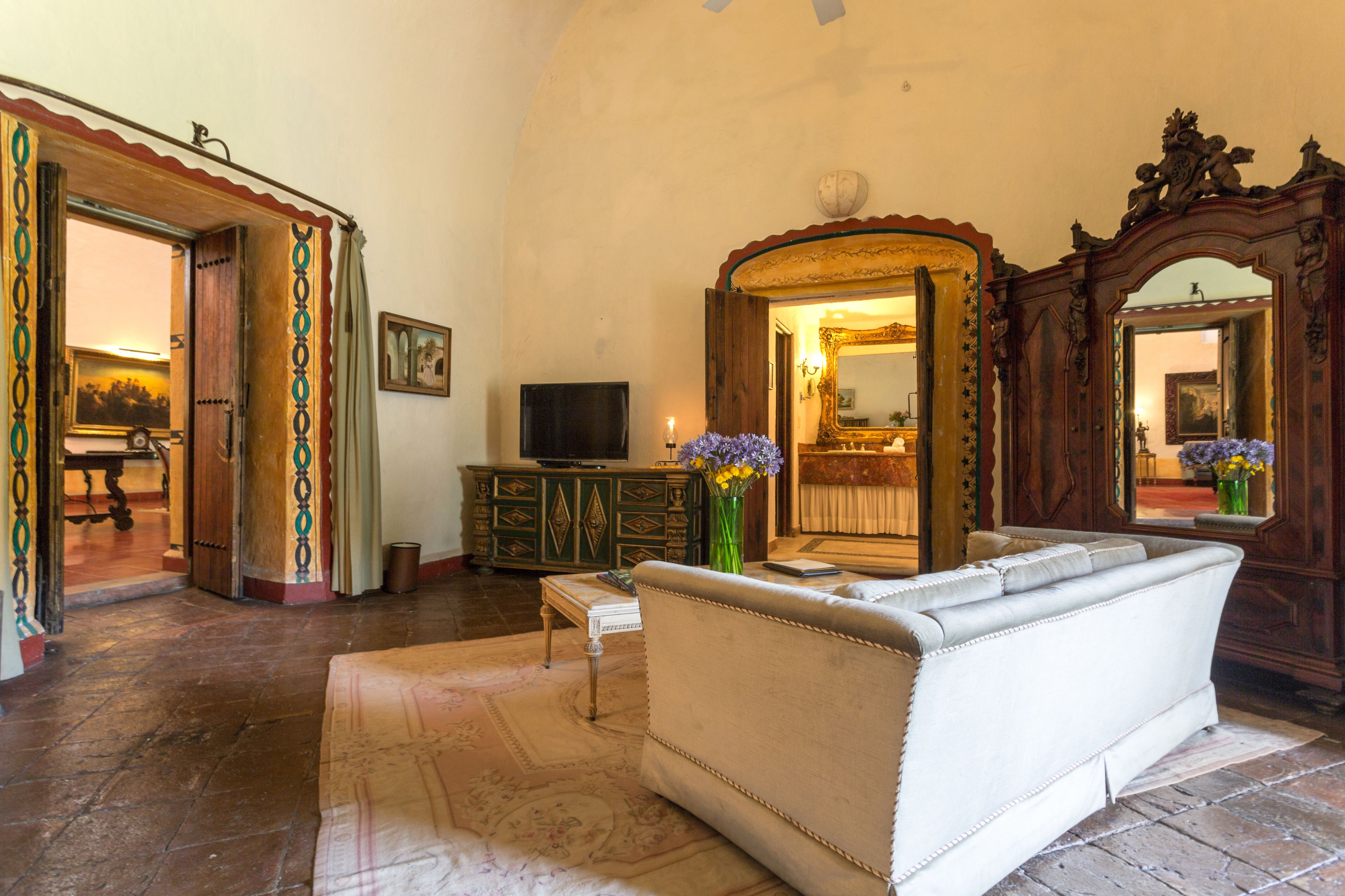 A living room with a sofa, a television, a cabinet, and a mirror.