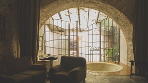 Une pièce avec une arche en pierre, une baignoire et un canapé.