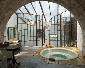 Un área de spa con un jacuzzi, una mesa de madera y un banco de piedra.