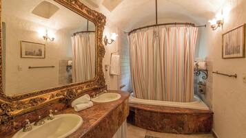 A bathroom with two sinks, a bathtub, a shower curtain, and a large ornate mirror.