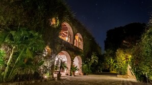 Un bâtiment historique doté d’arcades et d’une cour intérieure, le tout entouré d’une végétation luxuriante.