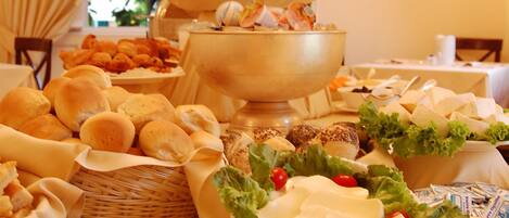 Ein Buffet mit verschiedenen Speisen, darunter Brot, Käse, Fleisch und Obst.