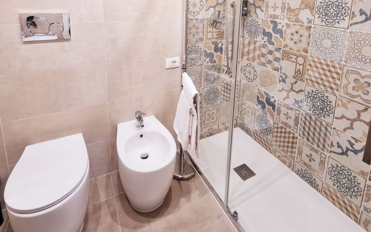 A bathroom with a toilet, bidet, and a glass shower enclosure.