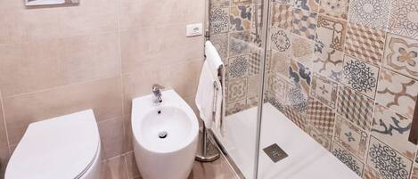 A bathroom with a toilet, bidet, and a glass shower enclosure.